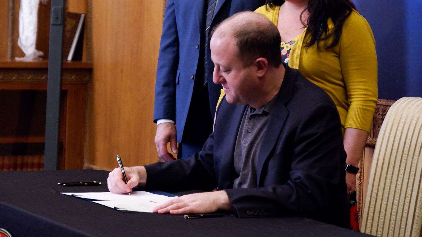Colorado Gov. Jared Polis signs a bill into law in his office at the state Capitol on Thursday, March 5, 2020. (Jesse Paul, The Colorado Sun)